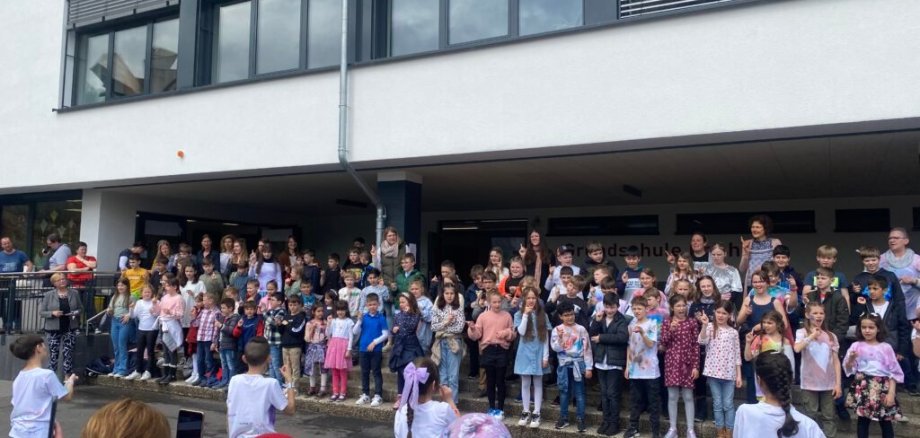 Alle Kinder der Grundschule Cochem stehen vor der Schule und singen.