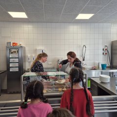 Frau Jarisch und Frau Ramadani verteilen das leckere Mittagessen an die Kinder.