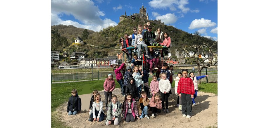 Alle Erstklässler haben sich auf dem Klettergerüst oder um dem Gerüst herum, zusammengefunden und posieren für das Foto.