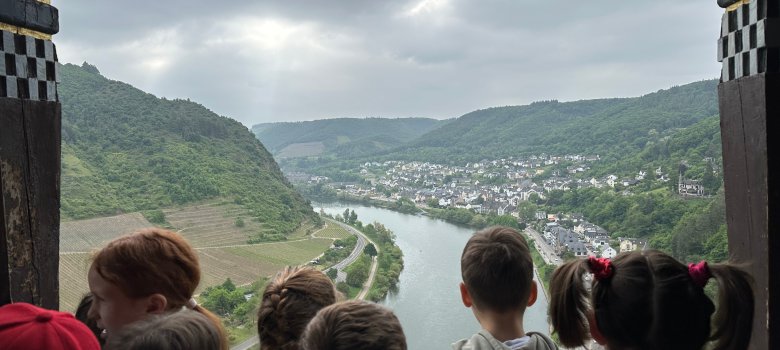 Klasse 1b schaut von einem Balkon der Reichsburg auf die Mosel herab