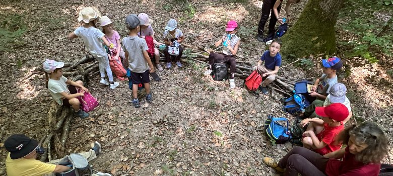 Wald-Picknick Kinder der 1b frühstücken auf ihrem Waldsofa im Sitzkreis