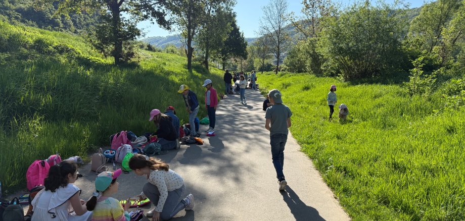 Die Kinder aller Klassen sitzen auf dem Weg und picknicken gemeinsam.